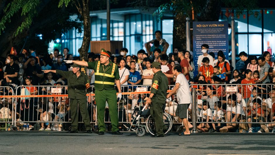 Vietnamese police manage a bustling nighttime crowd in Hanoi, ensuring public order.